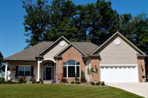 exterior of home with mix of vinyl and brick siding, asphalt shingle roofing, and trees in background