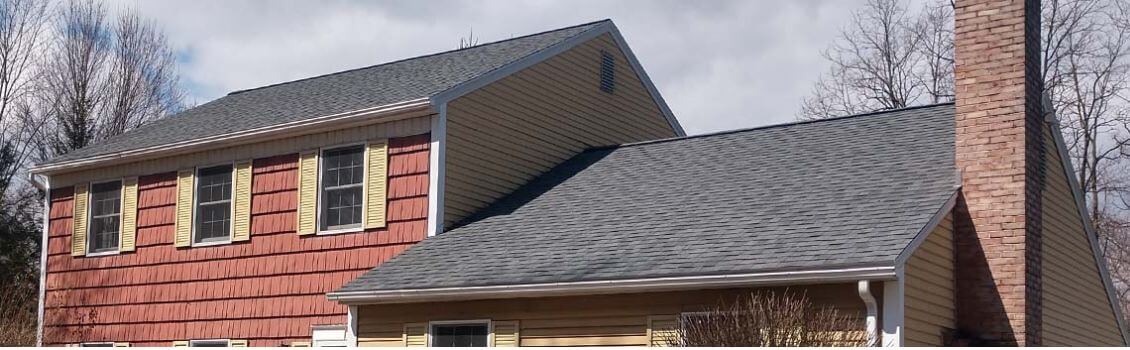 residential home with red siding, asphalt shingle roofing, and brick chimney