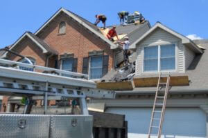 three roofing contractors installing asphalt shingles on roof